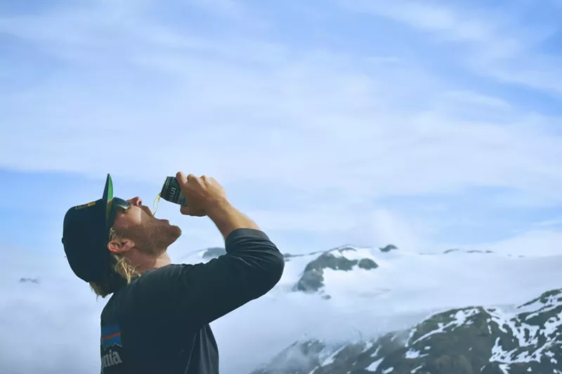 Image: Man drinks beer on top of mountain