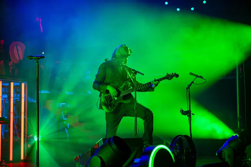 Image: man in a mask playing guitar in green lights