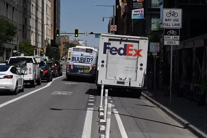 Image: A truck and a bus block a bike lane.