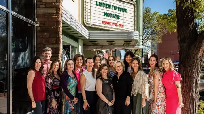 Women stand in front of a theater.