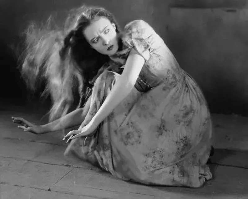 Image: woman in prairie clothes caught in wind crouched on the ground