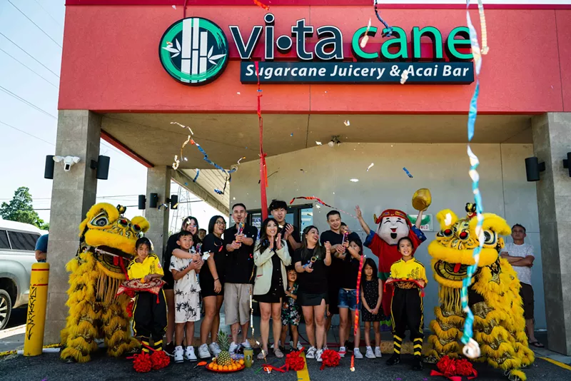Image: a group of people in front of a storefront with dragon dancers.