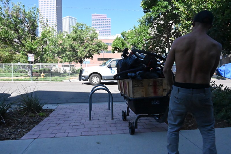 A homeless Denver resident pulls a wagon full of his stuff onto the sidewalk as Denver police begin forcing people to leave an encampment at 17th Avenue and Logan Street.