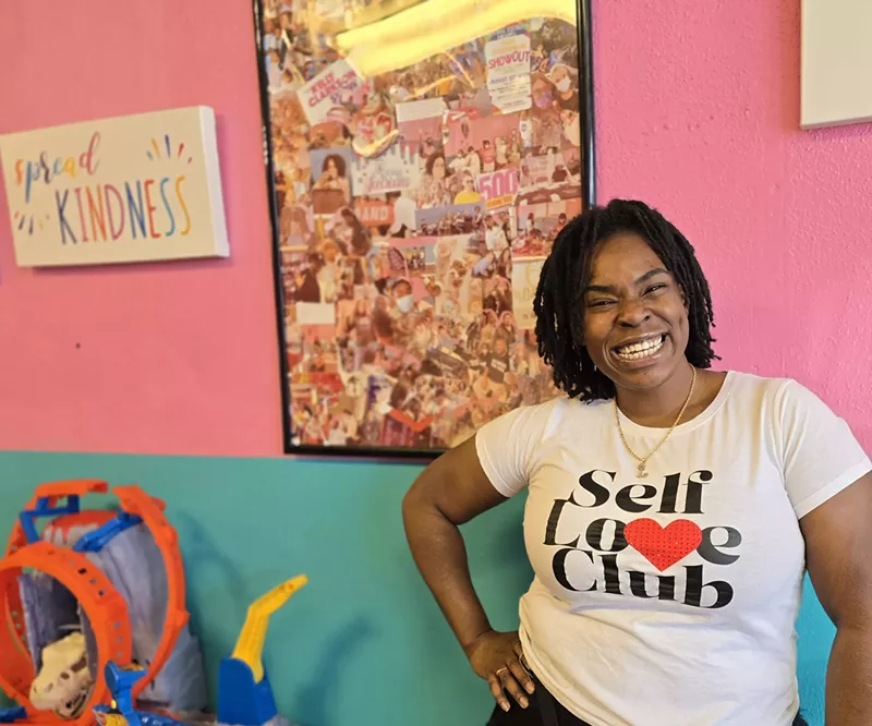 Image: woman posing in front of a blue and pink wall