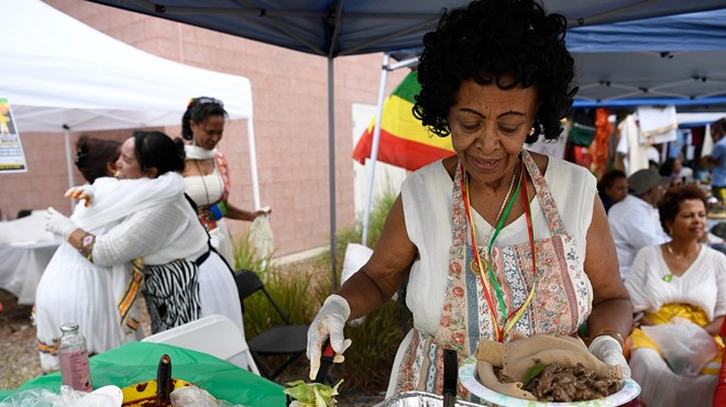 A woman serving a plate of injera and other Ethiopian dishes