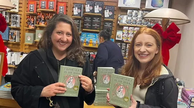 two women hold up books
