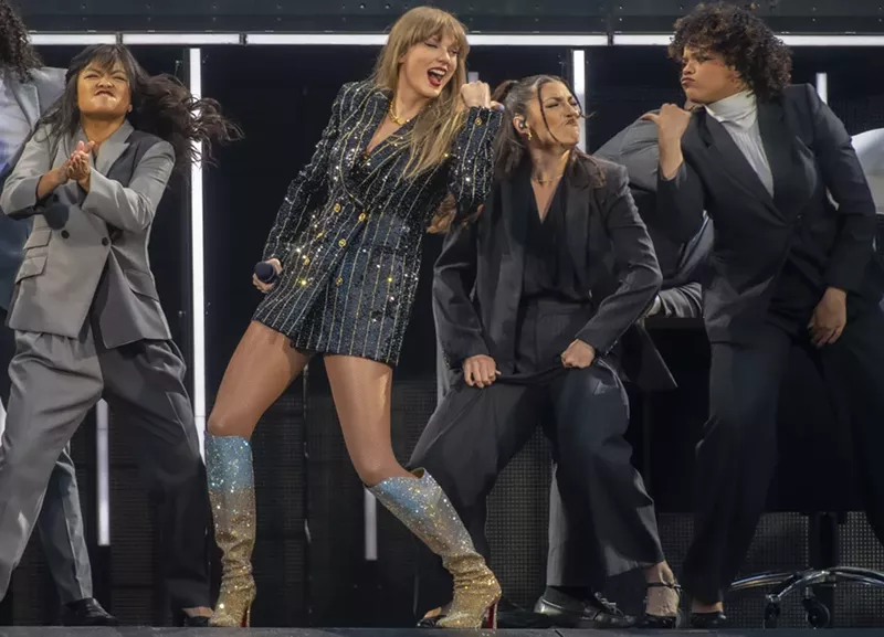 Image: A woman wearing a sparkly suit dances with friends.