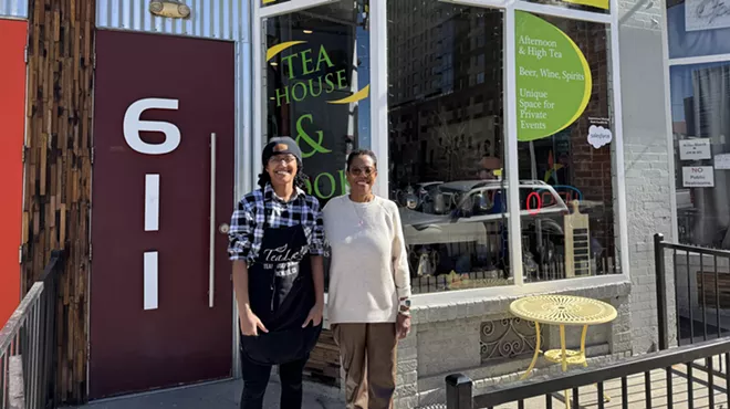 two people standing outside a tea shop