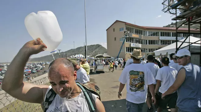 man pours water over his head on a hot summer day