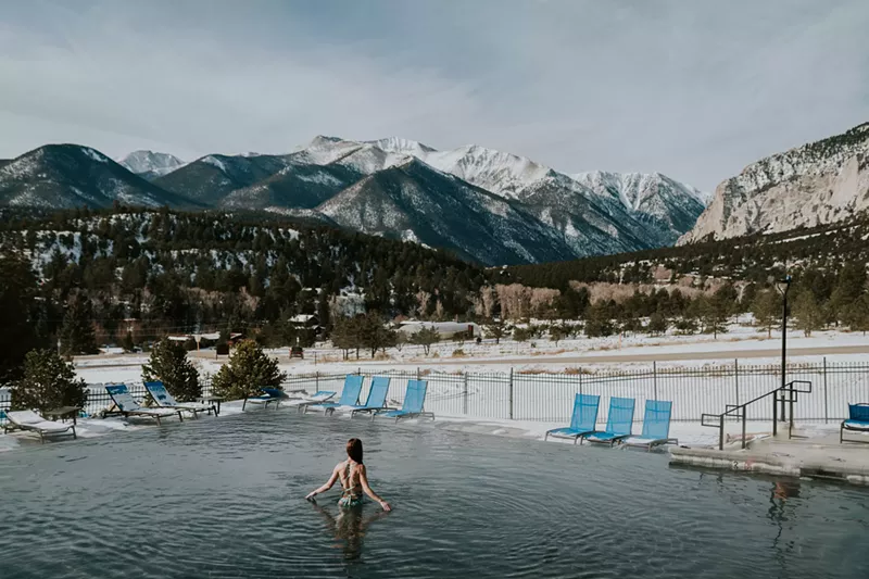 Image: A woman backdropped by snowy mountains while soaking in an infinity pool at Mount Princeton Hot Springs