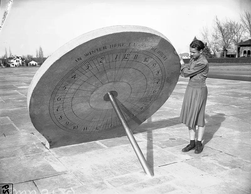 Image: An old photo of a woman standing by a sundial
