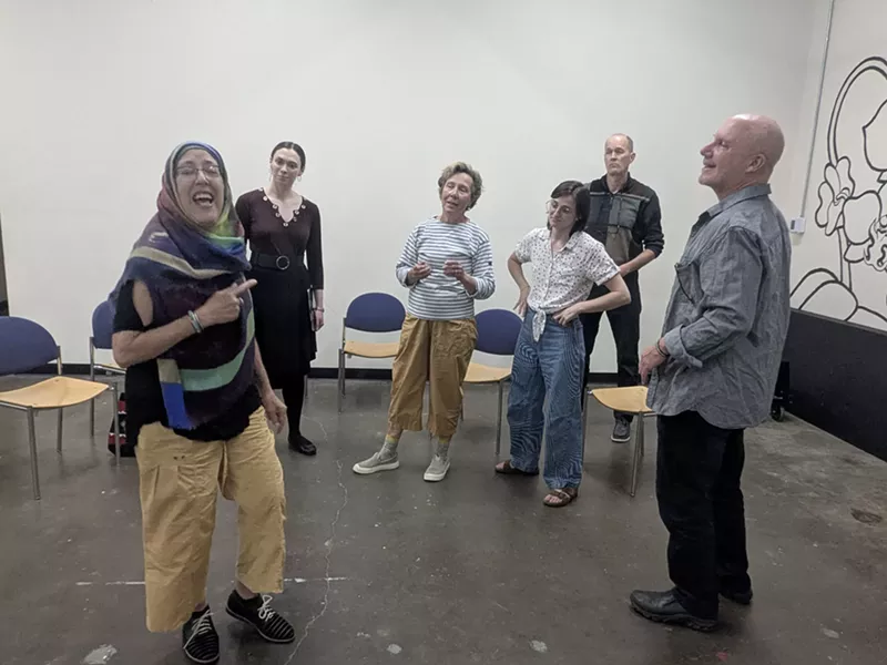 Image: A group of people stands in a room.