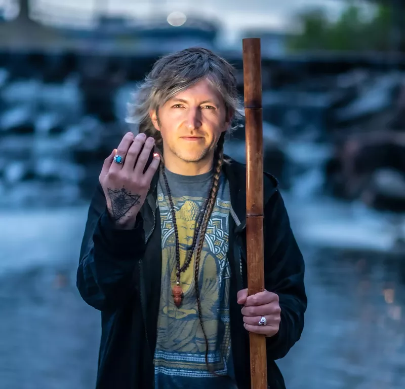 Image: man by river with stick and hand up