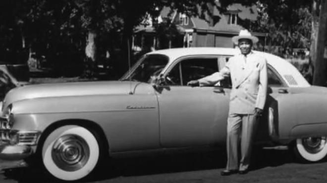 vintage photo of a man standing by a car