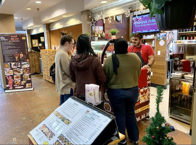 Image: Customers ordering from Mohamad Alnouri at Jasmine Syrian Food inside Mango House.