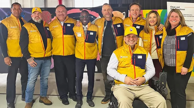 A group of people wearing yellow vests pose for the camera.