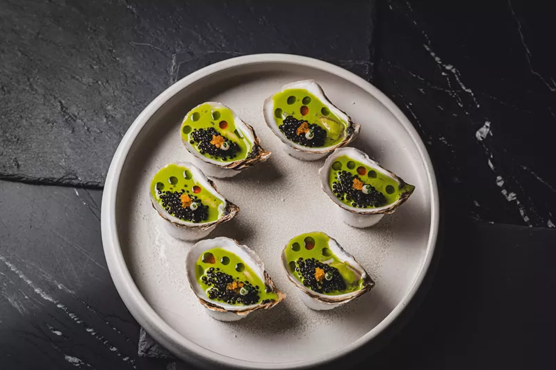 Image: a plate of oysters with green liquid in the shells