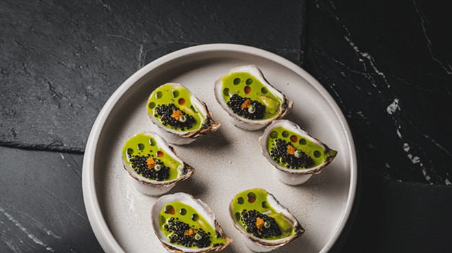 a plate of oysters with green liquid in the shells
