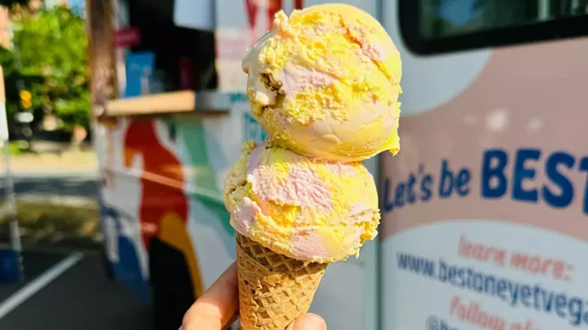 A person holding a vegan ice cream cone backdropped by Best One Yet's truck