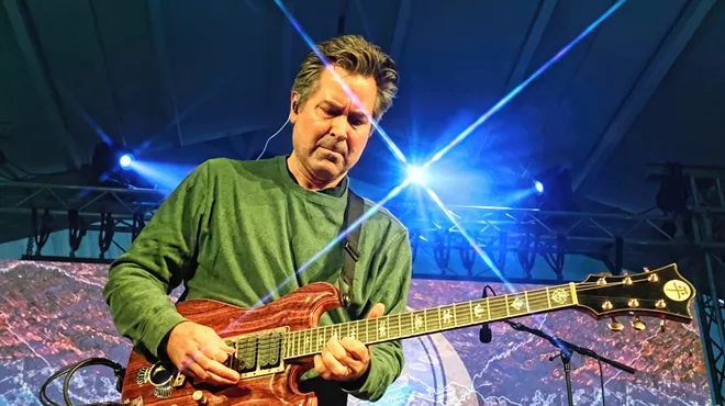 man playing guitar with lights in the background