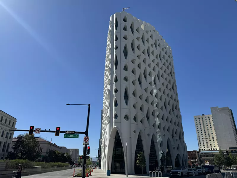 Image: tall building with weird windows against blue sky.