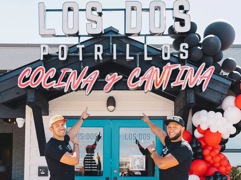 Image: two men in front of a door pointing at building sign