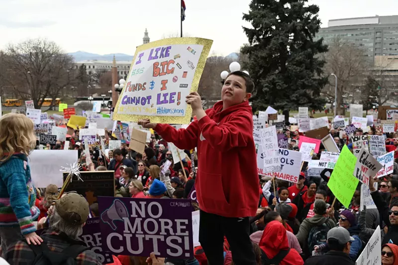 Image: A kid raises a sign.