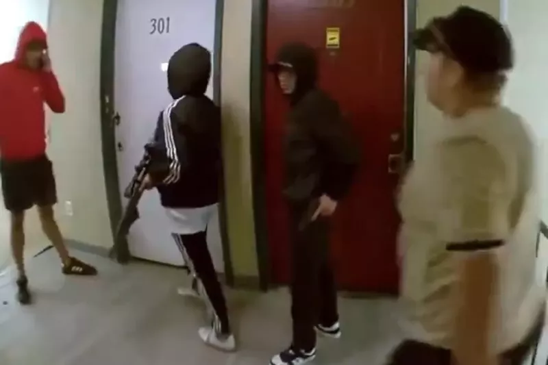 Image: Men with guns knock on an apartment door.