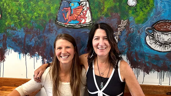 two women posting in front of a mural