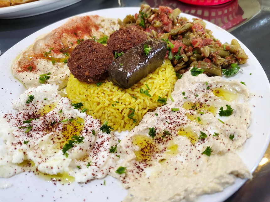 a platter with hummus, dolma, rice and green beans
