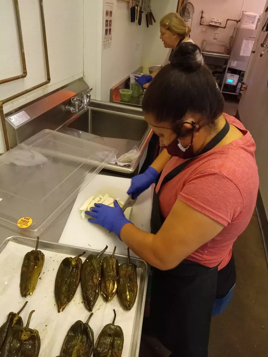 A participant in Comal Heritage Food Incubator's program prepares chiles for this week's special menu. - COMAL HERITAGE FOOD INCUBATOR