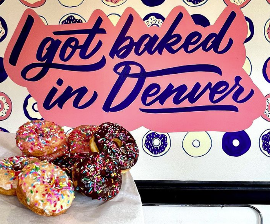 doughnuts with sprinkles in front of a sign that says I got baked in Denver