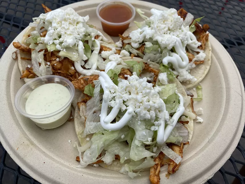 Chicken tacos topped with lettuce and sour cream.