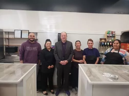 a line of five people stand in a commercial kitchen