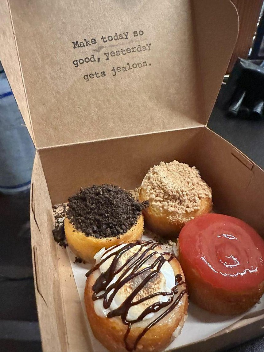 an open brown paper box with four small cheesecakes inside