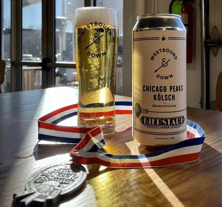 a glass of beer and a beer can with a silver medal on a red, white and blue ribbon