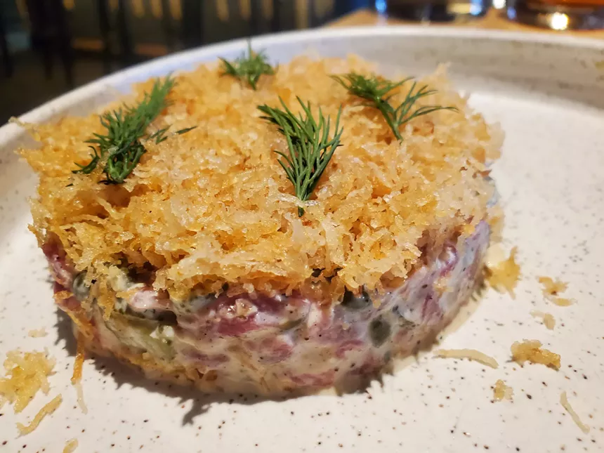 beef taratre topped with thin, crispy fried potatoes and dill.