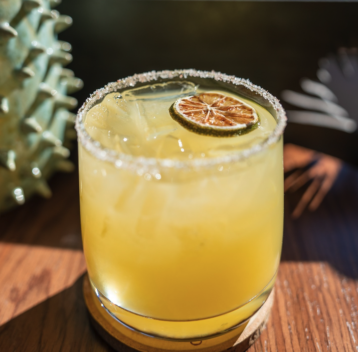 a yellow cocktail in a salt-rimmed glass
