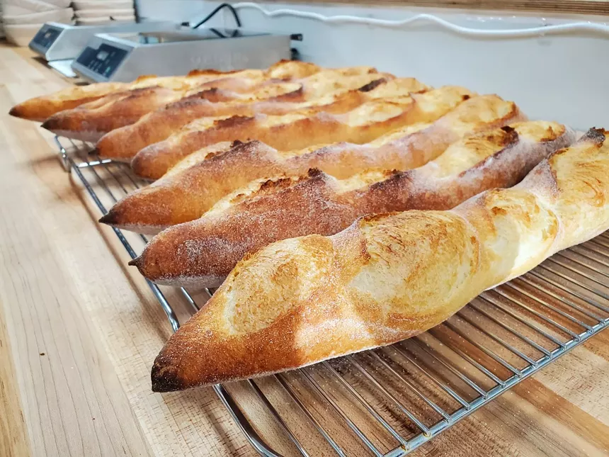 a line of baguettes cooling on a rack