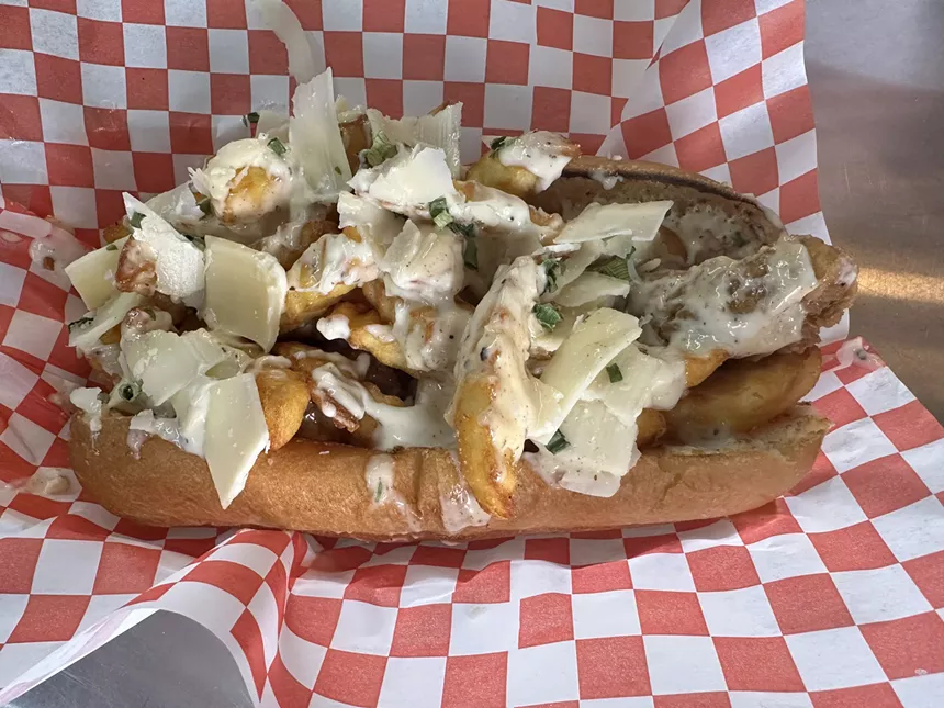 a sandwich on a hoagie roll served on red and white checkered paper