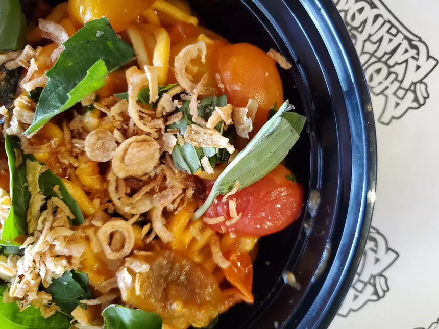 a bowl of noodles with cherry tomatoes, basil and crispy shallots