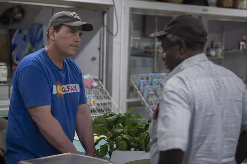 a man in a hat and blue t short talks with a customer in a store