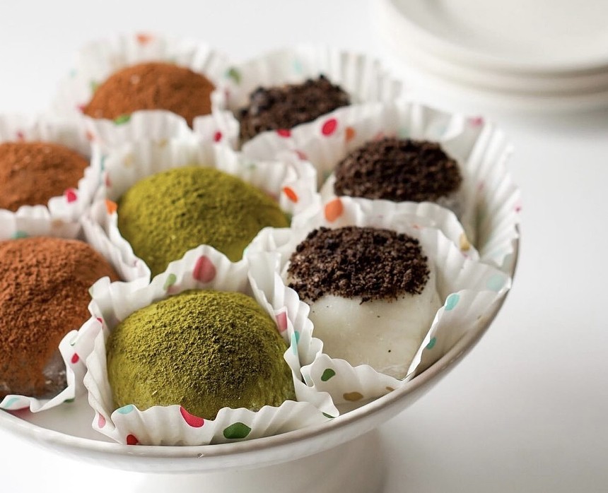A serving dish layered with different flavored mochi lined with cupcake wrappers.