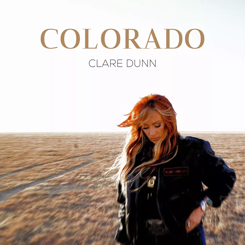 a woman stands in a field for an album cover