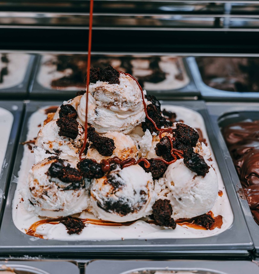 An ice cream that has been topped with brownie pieces and drizzled with dulce de leche sauce.
