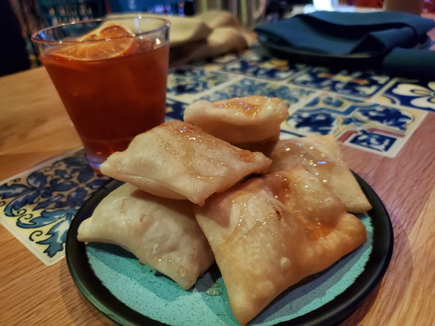 sopaipillas on a place with a cocktail in the background