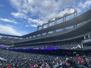 A stadium that isn't even half full sits against a backdrop of blue sky and fluffy clouds.