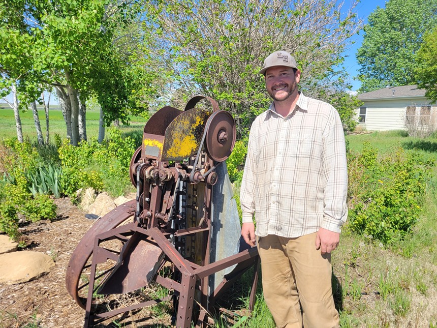man in front of old farm machine