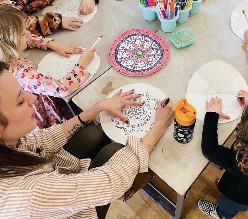 woman and children draw mandalas at a work table