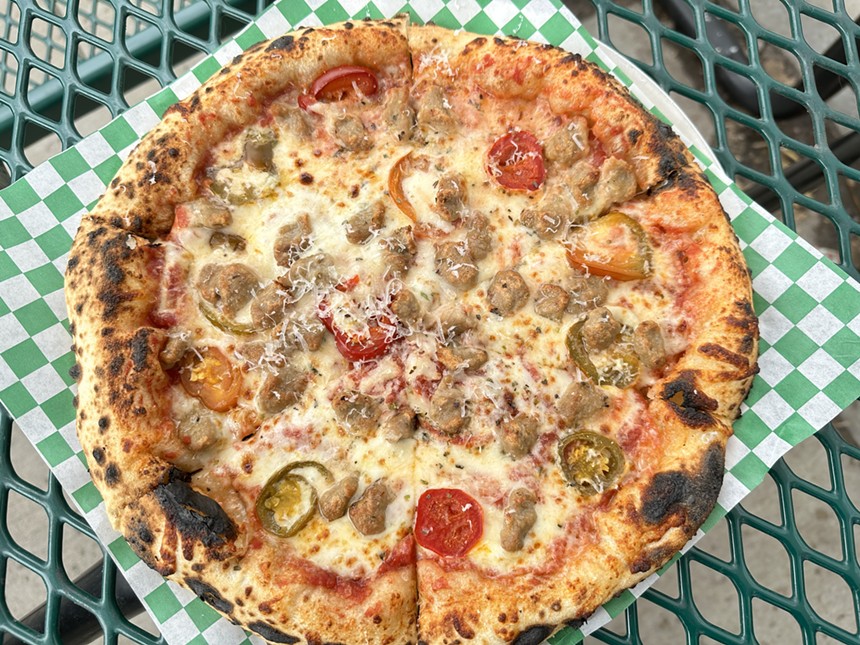 a pizza topped with Marinara, Italian sausage, spicy peppers, mozzarella, parmesan and oregano